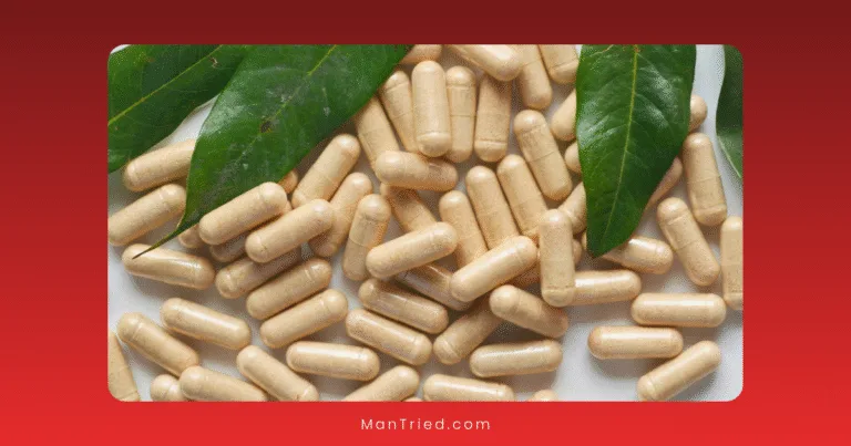 A pile of beige capsules scattered on a surface with two large green leaves on top, set against a red background—suggesting ashwagandha for testosterone.