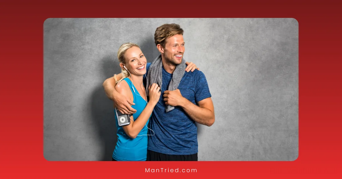 A smiling woman and man in athletic wear pose together, with the man’s arm around the woman. She holds an MP3 player and both have towels, ready to discover the best time to exercise for sexual performance against a neutral gray background.