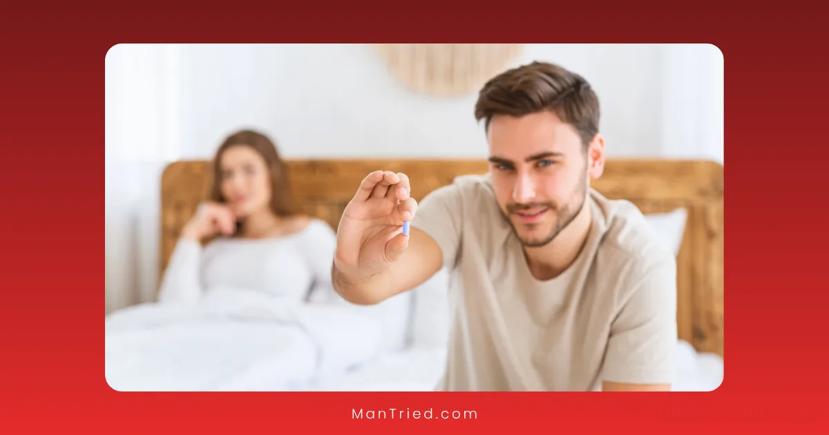 A man sitting on the edge of a bed holds up a blue pill and smiles at the camera—boosting libido—with a woman in the background looking away.
