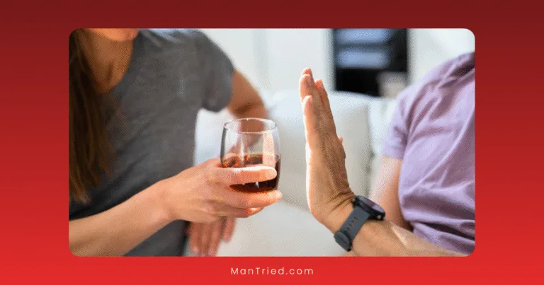 A person offers a glass of alcohol to another, but the other refuses with a stop gesture. They're sitting on a couch indoors, possibly discussing foods that lower libido and making mindful choices together.