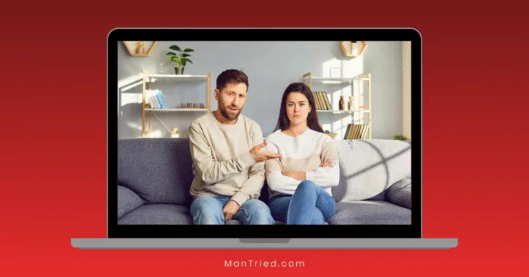 A man and woman sit on a gray couch, visible on a laptop screen during an online sex therapy session. The man gestures as if explaining something, while the woman sits with arms crossed, looking upset in their bright, modern living room.