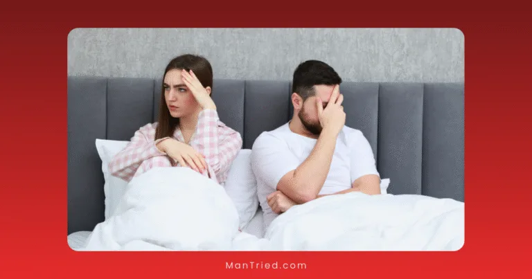 A woman and a man sit in bed, both looking upset and avoiding eye contact, perhaps strained by the psychological causes of delayed ejaculation. The woman has her hand on her forehead, while the man covers part of his face with his hand.