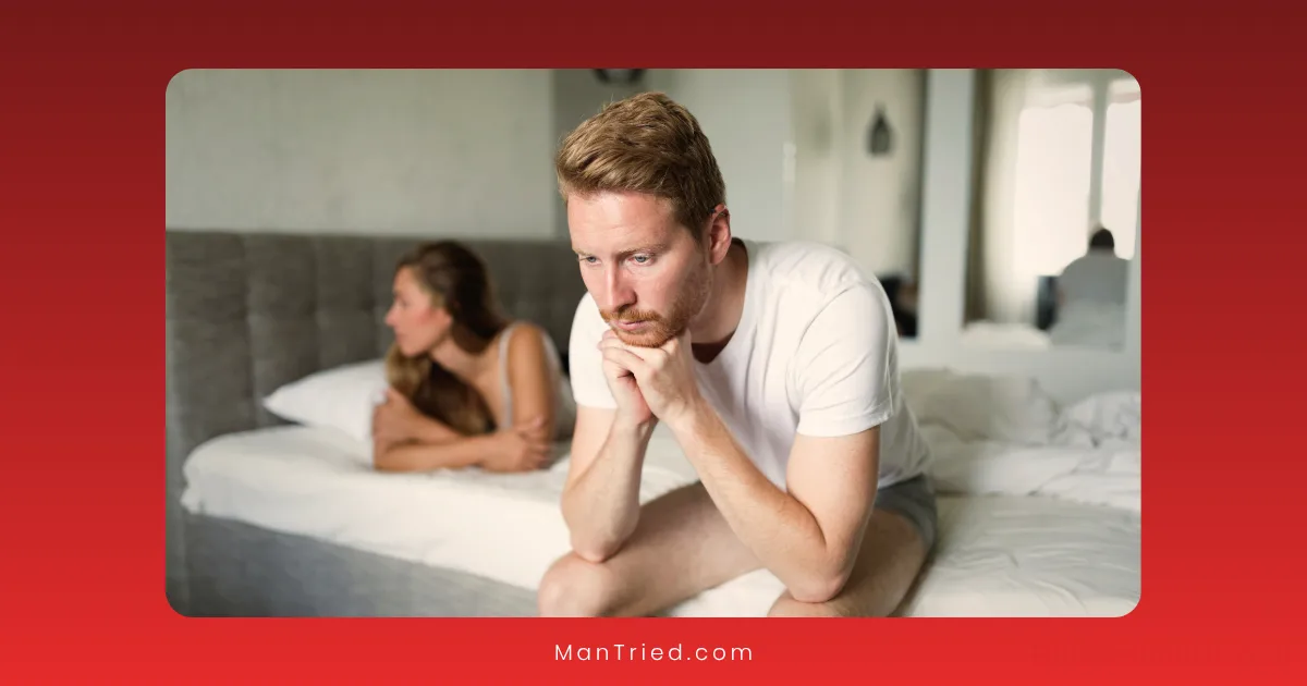 A man sits on the edge of a bed looking worried, hands clasped under his chin, while a woman lies behind him facing away. The tense mood suggests it might help to talk to your partner about premature ejaculation.