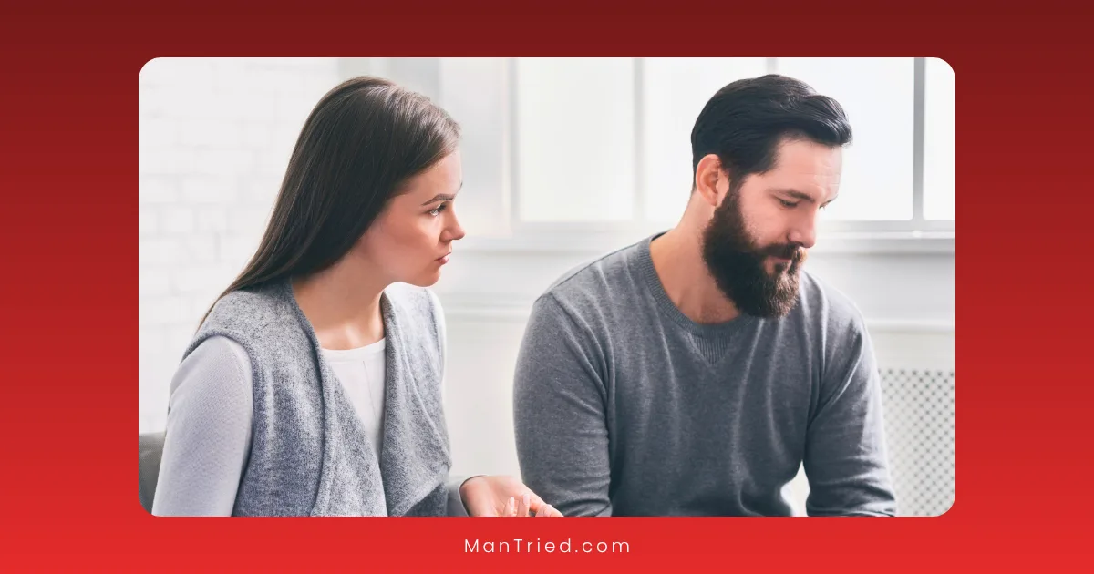 A woman and a man sit indoors in long-sleeve shirts. The woman looks at the man with concern as he gazes down, appearing sad or thoughtful—perhaps reflecting on his experience with antidepressants. The background is softly lit.