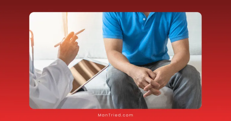 A man in a blue shirt sits on a couch with his hands clasped, facing a healthcare professional holding a clipboard and pen during a consultation about cultural stigmas.