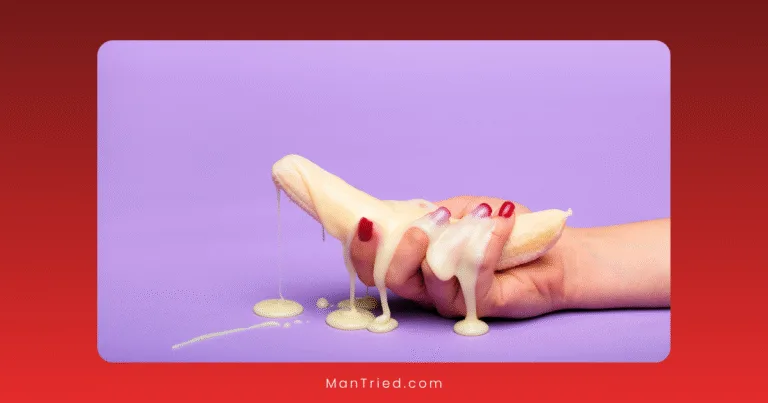 A hand with red-painted nails holds a peeled banana covered in dripping white liquid against a purple background, evoking imagery often associated with non-ejaculatory orgasms.