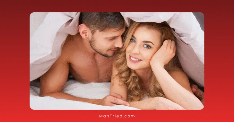 A man and woman lie closely together under a white blanket, smiling contently as they enjoy intimate positions and techniques. The woman faces the camera with her head on her hand, while the man gazes at her against a soft red gradient background.