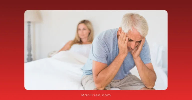 An older man sits on the edge of a bed with his head in his hands, looking distressed—perhaps worried about the prostate-ED connection. A woman sits in the background, watching him with a concerned expression in the calm, neutral-toned room.