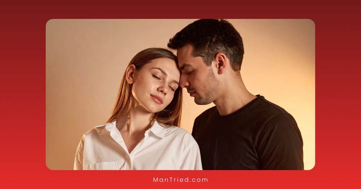 A young couple stands close together; the woman in a white shirt has her eyes closed, leaning gently toward the man in a black shirt as they find comfort, even with sensory processing disorders. The background is softly lit.