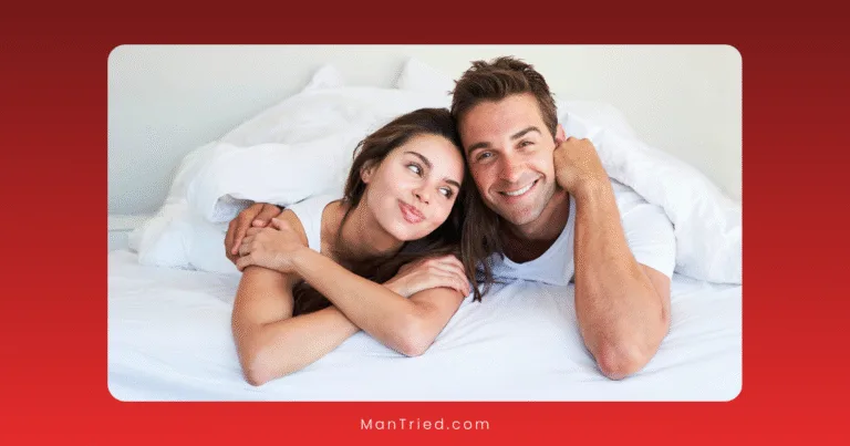A smiling couple lies on a bed under white blankets, looking content and relaxed, radiating sexual confidence.