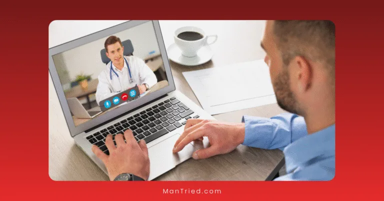 A man sits at a desk using his laptop for a video call with a doctor about virtual ED treatment. A cup of coffee, a pen, and paper are on the desk. The screen shows the doctor wearing a white coat and stethoscope.